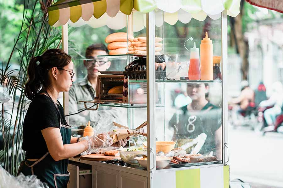 A vendor preparing Banh mi on a bustling street